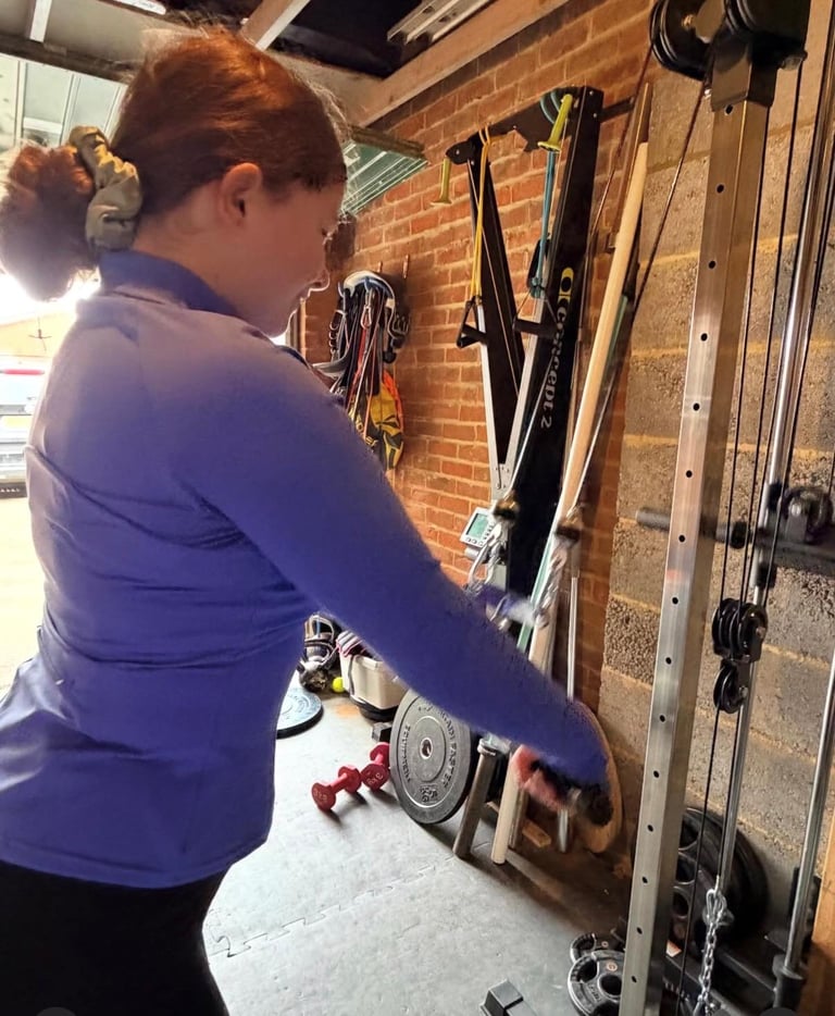 Person in blue shirt working on bicycle mounted on wall rack in garage workshop with exposed brick